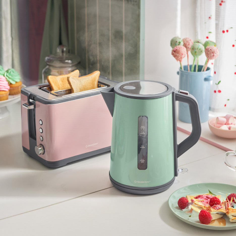 Roze broodrooster met toast en mintgroene waterkoker op een aanrecht.