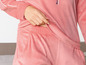 Een roze velours pyjama met een witte streep aan de mouw.