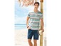 Man in een gestreept T-shirt en jeans shorts op het strand.