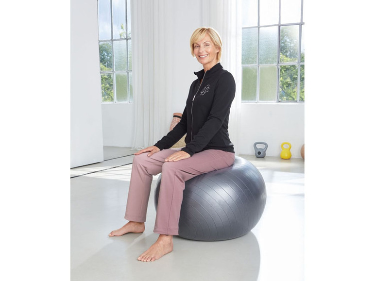 Vrouw zit op een grote, grijze fitnessbal.