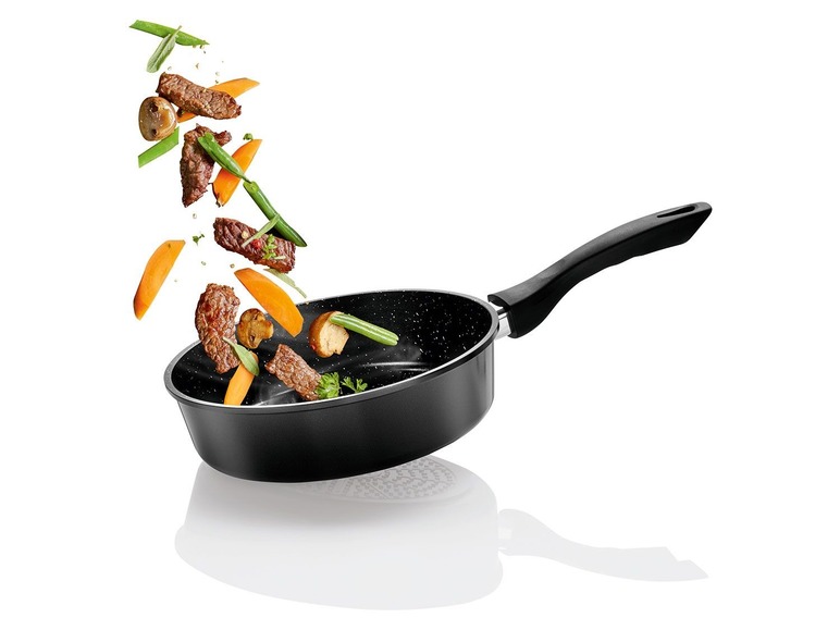 Een zwarte pan met vlees, groenten en champignons erboven