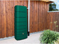 Een groene regenwaterton voor buiten naast een houten muur.