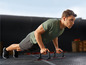 Man doet push-ups met behulp van push-up bars.