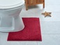 Een witte toiletpot met een rood badmatje in een badkamer.