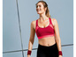 Een vrouw draagt een rode sportbeha en zwarte leggings.