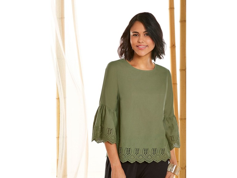 Een vrouw draagt een groene blouse met kantdetails.