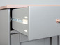 Een open lade van een grijs dressoir met metalen geleiders.