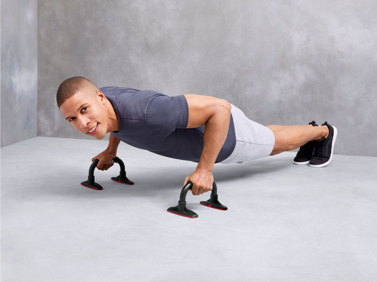 Man doet push-ups met behulp van push-up bars.