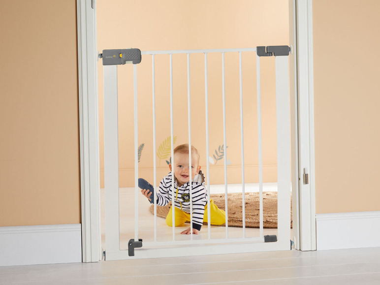 Een baby achter een witte veiligheidspoort van Summer Infant.