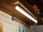 Een witte LED-strip verlichting onder een houten plank in een keuken.