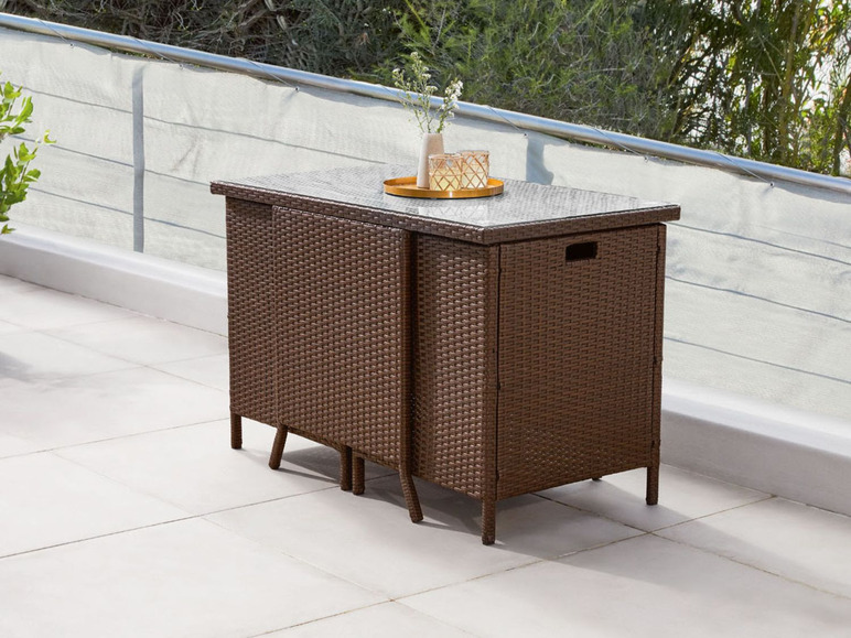 Wicker tuinmeubelen met glazen tafelblad op een balkon.