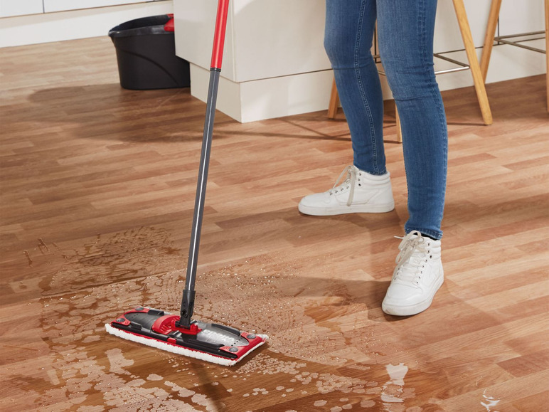 Een persoon veegt met een Vileda mop op een houten vloer.