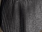 Een zwarte, geplooide rok met een glitterende textuur.