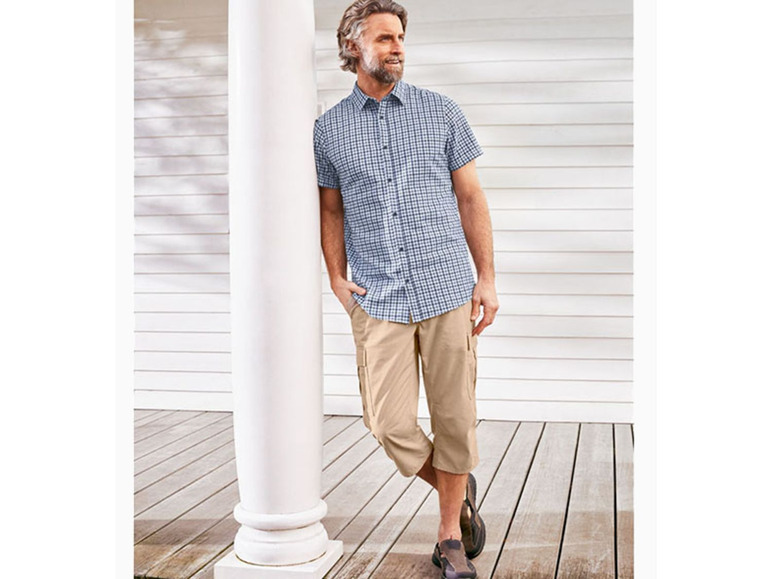 Man in een geruit overhemd en beige chino's.