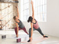 Twee vrouwen doen yoga op matten met blokken.
