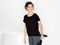 Vrouw in zwarte T-shirt en leggings, die sportkleding presenteert.