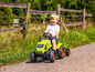 Een kind rijdt op een groene Claas tractor.