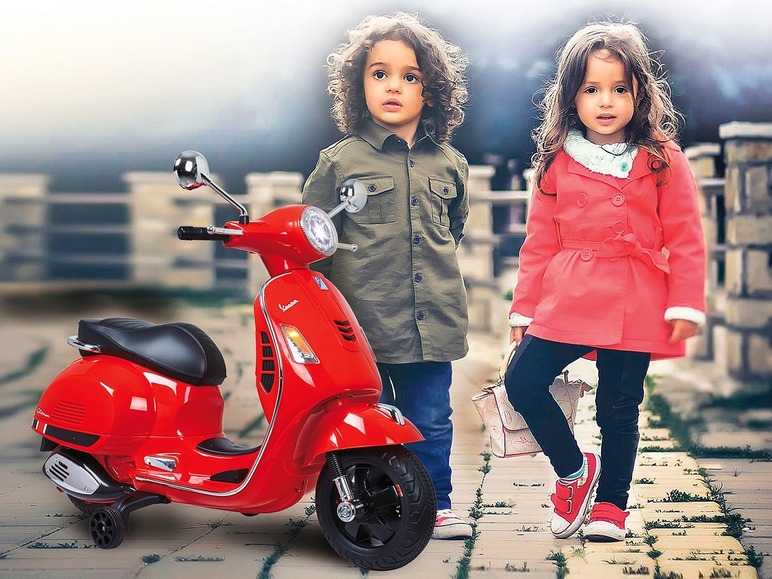 Twee kinderen poseren naast een rode Vespa-scooter voor kinderen.