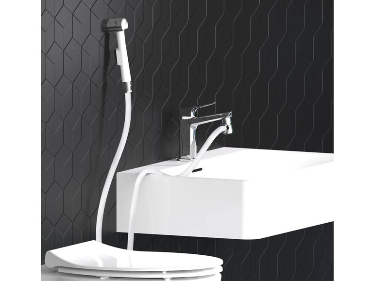 Een bidet sproeikop en wastafel in een moderne badkamer.