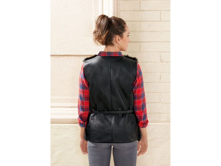 Een vrouw draagt een zwarte leren vest met een rode geruite blouse.