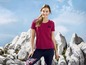 Een vrouw draagt een roze T-shirt met 'Back to Nature' erop en blauwe leggings.
