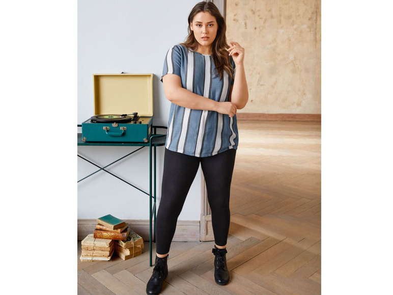 Een vrouw draagt gestreepte top en zwarte leggings.