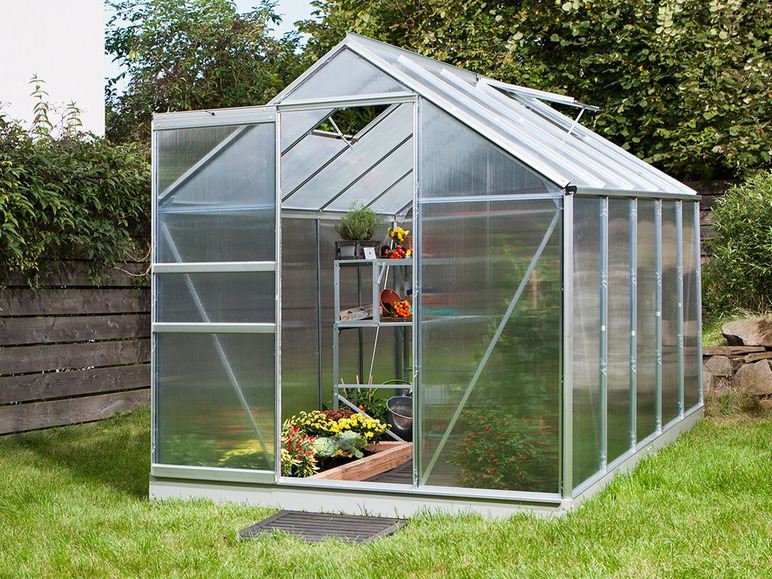 Een kleine glazen kas met een deur en een raam.