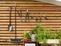 Tuingereedschap, waaronder een schop, hark, snoeischaar en een gieter, hangen aan een houten schutting.