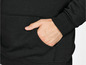 Een close-up van een zwarte hoodie met een hand in de zak.