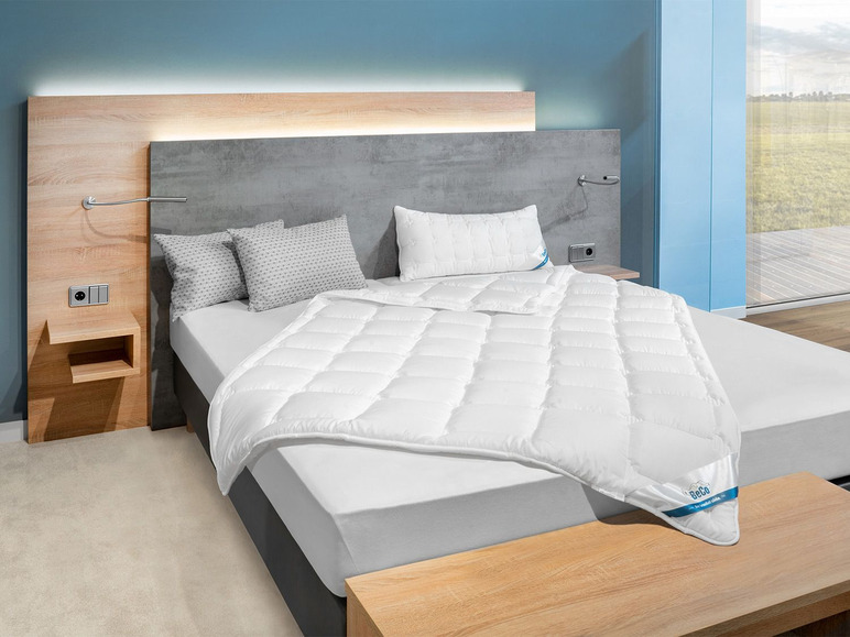 Een wit dekbed van Beka op een bed in een slaapkamer.