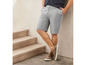 Man draagt grijze shorts en bruine sneakers.