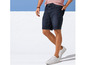 Man in jeans shorts en witte sneakers.