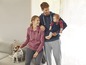 Een gezin met een hond draagt comfortabele hoodies en joggingbroeken.