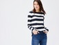 Een vrouw draagt een gestreept longsleeve shirt en blauwe jeans.