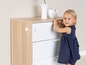 Een kind probeert een lade te openen, beveiligd met een kinderbeveiliging.
