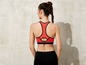 Een vrouw draagt een rode sportbeha en zwarte leggings.