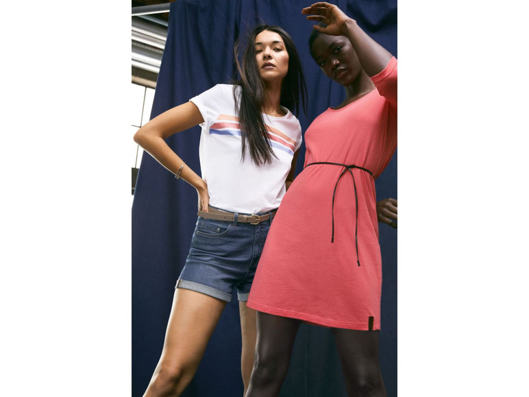 Twee vrouwen poseren in een roze jurk en een denim short.