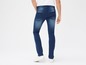 Man draagt blauwe skinny jeans en witte sneakers.