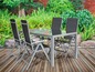 Tuinset met vier stoelen en glazen tafel op een houten terras.