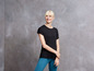 Een vrouw draagt een zwarte T-shirt en blauwe leggings.