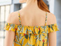Een geel bloesje met een tropisch printje en ruches.