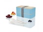 Een blauwe lunchbox met houten deksel, bestek en fruit.