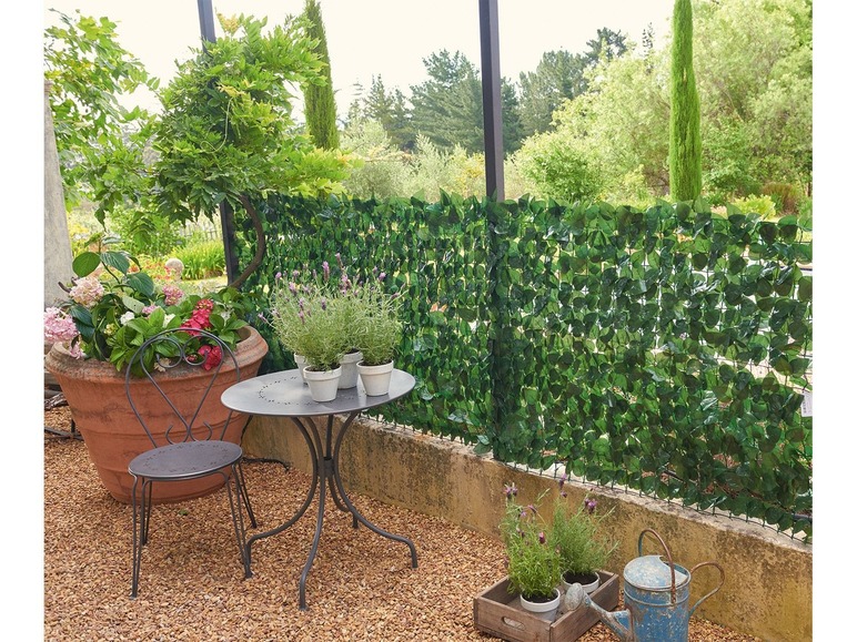 Kunststof groene haag met een stalen tuinstoel en tafel