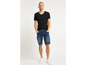 Man in een zwarte T-shirt en blauwe denim shorts.