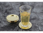 Een glas met drank op een gouden onderzetter en een stapel gouden onderzetters.
