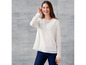 Een vrouw draagt een witte blouse met ruches en blauwe jeans.