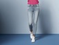 Een vrouw draagt ​​lichtblauwe skinny jeans met witte sneakers.
