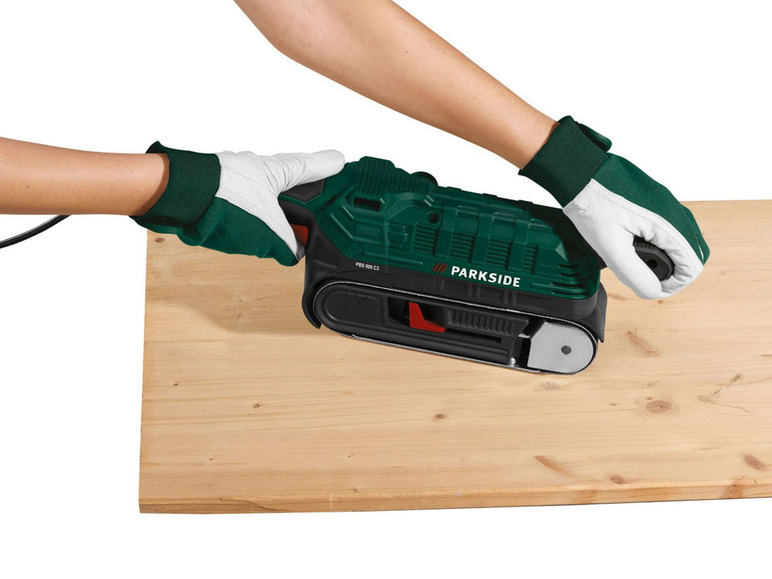 Een hand gebruikt een Parkside schuurmachine om hout te schuren.
