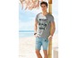 Man draagt een grijs T-shirt met 'Miami Beach Side' print en blauwe denim shorts.
