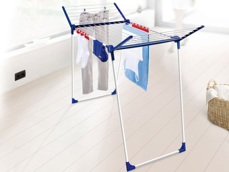 Een wit en blauw droogrek met kleding, waaronder een broek en een handdoek.